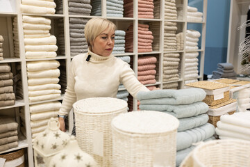 A woman tries on clothes in a store. She stands in front of a mirror surrounded by various products...