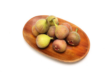 白背景の木製の皿にのせたイチジク