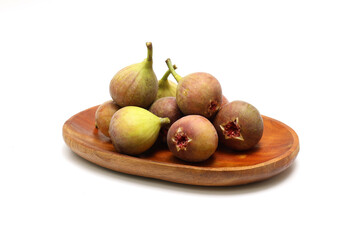 白背景の木製の皿にのせたイチジク