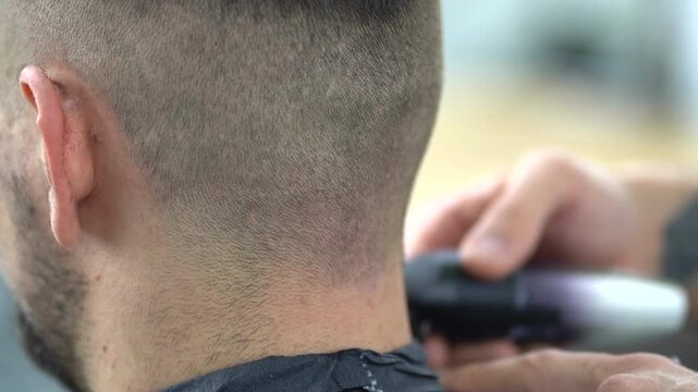 Barber trims the back of the head with a clipper in a modern barbershop, focusing on precision and clean lines for a sharp, polished haircut