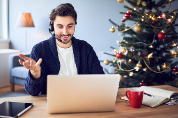 Cheerful man with headset having video call during Christmas time