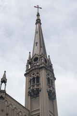 Obraz premium Gothic church steeple with cross under cloudy sky