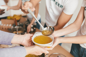 Volunteers gather to prepare and serve warm soup in a community kitchen. Participants pass bowls filled with soup, fostering kindness and connection among attendees during the event.