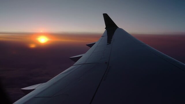 Aerial passenger window view shows an airliner wing and winglet at sunset near Funchal, Madeira, with low cloud, rich dusk colors, and a subtle bank in flight.