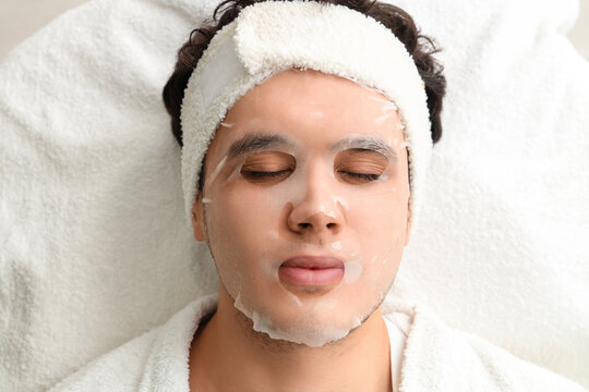 Young man with facial sheet mask in beauty salon, top view