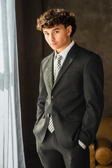 Portrait of a smiling teenage boy smartly dressed in a prom suit and tie, casually standing with his hands in his pockets  © 3Days2Go Media