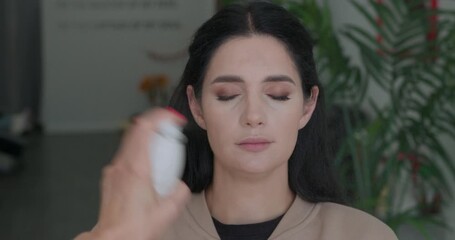 Application of makeup setting spray by a makeup artist on a clients face.
