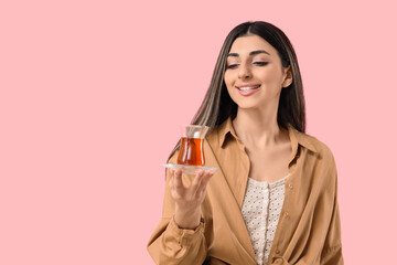 Young woman with Turkish tea on pink background