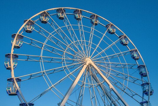 A large Ferris wheel with white structures and blue-and-cyan gondolas - Powered by Adobe