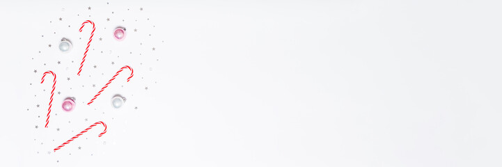 Minimal Christmas background with candy canes, baubles and silver confetti on white copy space for festive banners, ads, sales and social media designs