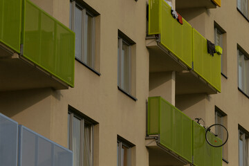 Green balcony with bicycle wheel planter, cyclist role implied by parked bike and lock details, close view of railing and pots, domestic urban lifestyle snapshot with textured concrete background