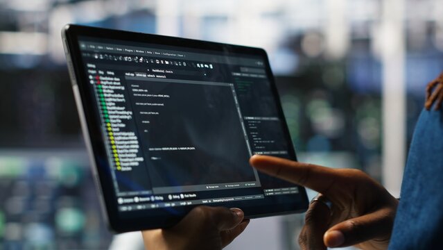 Close up of data center software developer checking code on tablet used to update equipment. Server hub expert using programming language script on device to do maintenance, camera B - Powered by Adobe