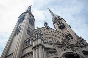 Impressive gothic church towers and ornate stone façade captured from a low angle against a bright cloudy sky