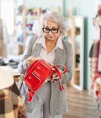 Senior woman at trading floor pick out and buying handbag. Off line clothing and accessories store...