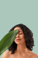 Naklejka premium Young African-American woman with palm leaf on green background, closeup