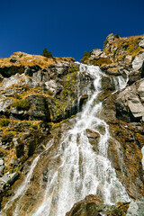 Stunning Capra Waterfall cascading over rocky cliffs in Fagaras mountains. View from Transfagarasan Highway, Romania