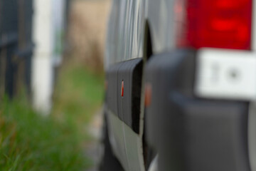 blurred van side and taillight foreground, shallow depth of field capturing wet panel and soft...