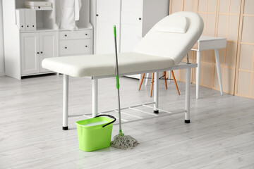 Green bucket with mop near couch in medical office