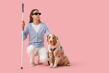 Blind young woman with guide dog on pink background