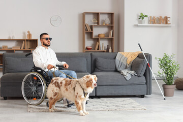 Blind young man in wheelchair with guide dog at home