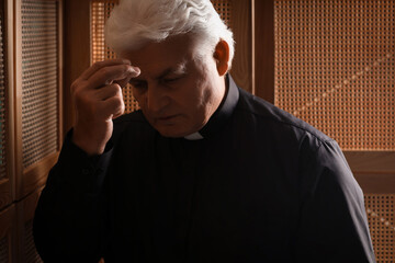 Senior priest crossing himself in confession booth