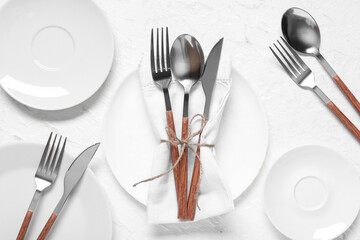 Plates with silver cutlery and napkin on white background