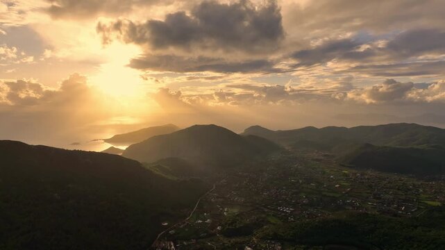 Aerial drone shot of mountains lit by golden sunset tones, capturing calm and majestic nature.