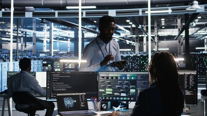 Server hub manager talking with programmer using node tree software to optimize system health. Data center supervisor overseeing IT expert analyzing equipment issues using AI visualization, camera A