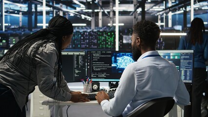 Data center supervisor overseeing work done by engineer using deep learning algorithms to analyze...