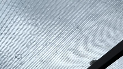 Heavy rain drumming on the transparent plexiglass roof. Beautiful rainy scene on summer day. Concept of tranquility nature scene. Close up Slow motion