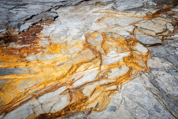 Detailed close-up of natural rock texture with striking orange iron oxide veins and grey slate layers, abstract geological pattern