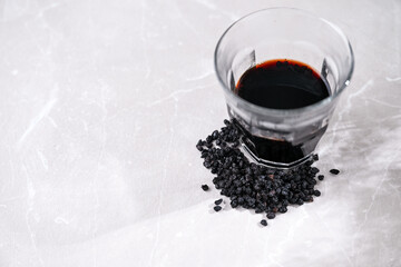 Dried Elderberry Berries and Glass of Syrup on White Background