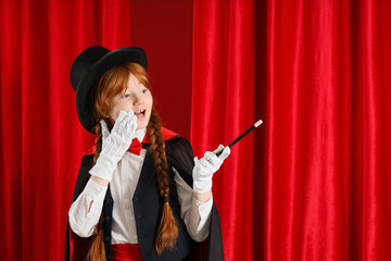 Surprised young magician with magic wand on red curtain background