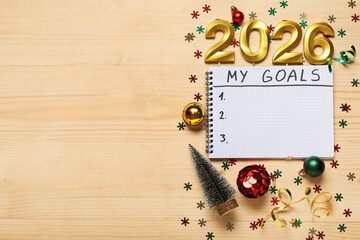 Notebook with to-do list, candles in shape of figure 2026 and Christmas decor on brown wooden background