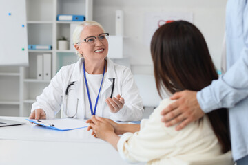 Fototapeta premium Female fertility doctor with couple talking about IVF at table in clinic