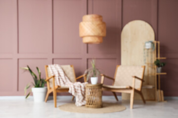 Comfortable armchairs with table and hanging lamp near brown wall in living room