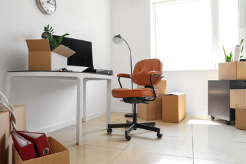Interior of office with workplace, lamp and cardboard boxes on moving day