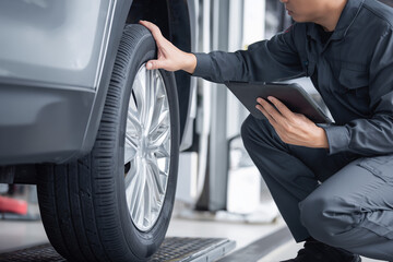 Car maintenance inspection, mechanic checking tyre, light background, copy space