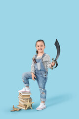 Fototapeta premium Cute little girl with toy sword and adventure books on blue background