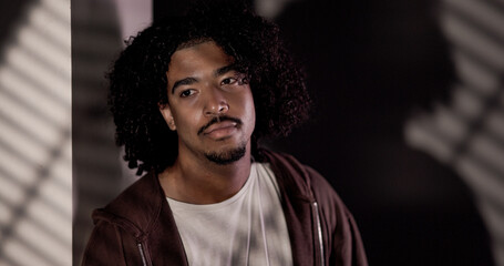 Studio shot of a handsome African American man with curly hair posing in studio lighting. This image is suitable for fashion beauty and editorial content.
