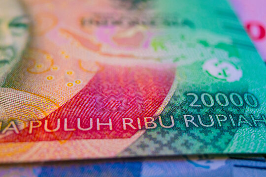 Close-up of a 20,000 Indonesian Rupiah banknote. The text "DUA PULUH RIBU RUPIAH" is visible alongside the 20000 denomination, a map of Indonesia, and the portrait of G.S.S.J. Ratulangi in green tones
