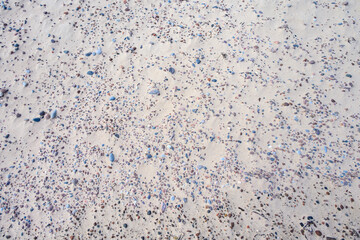 Sandy beach with small pebble rocks in random patterns, as a nature background
