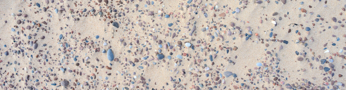 Sandy beach with small pebble rocks in random patterns, as a nature background
