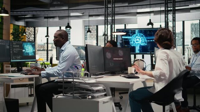 Inexperienced intern in office requests help from team to fix hacking attempt on corporate network. Coworkers investigate unauthorized access alerts, brainstorming ways to mitigate damages, camera A