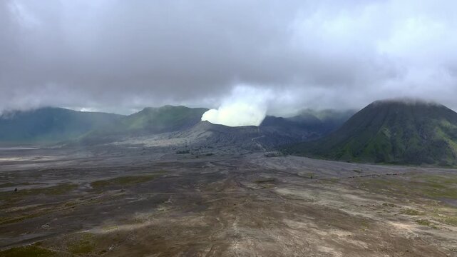 Clouds of smoke coming from crater of Mount Bromo and drifting by, Tengger Semeru national park, East Java, Indonesia. Landscape with erupting volcano in sunny day. Eruption and volcanic activity.