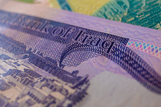 A macro shot displays a 50,000 Iraqi Dinar note, emphasizing its holographic palm tree security patch, intricate green intaglio scrollwork, and a section of a stylized historic landscape.