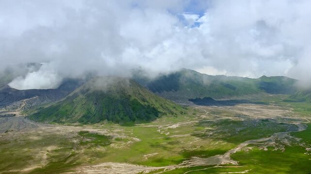 Clouds of thick white smoke emitted by erupting volcano and drifting over ground. Mount Bromo eruption. Tengger Semeru National Park. East Java, Indonesia. Bird's eye view. Long shot. Still camera.