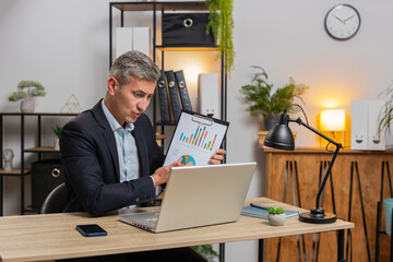 Young businessman working on laptop at office desk talking on online communication video call with employee, boss shows graphical analytics. Manager man support services looking at webcam of computer.