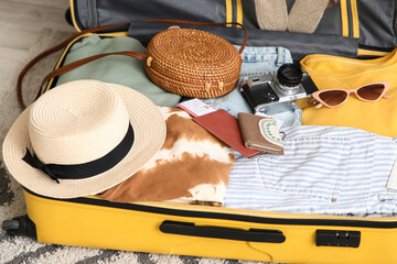 Unpacked suitcase with clothes and travelling accessories in hotel room