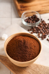 Bowl of coffee powder with beans on white tile background